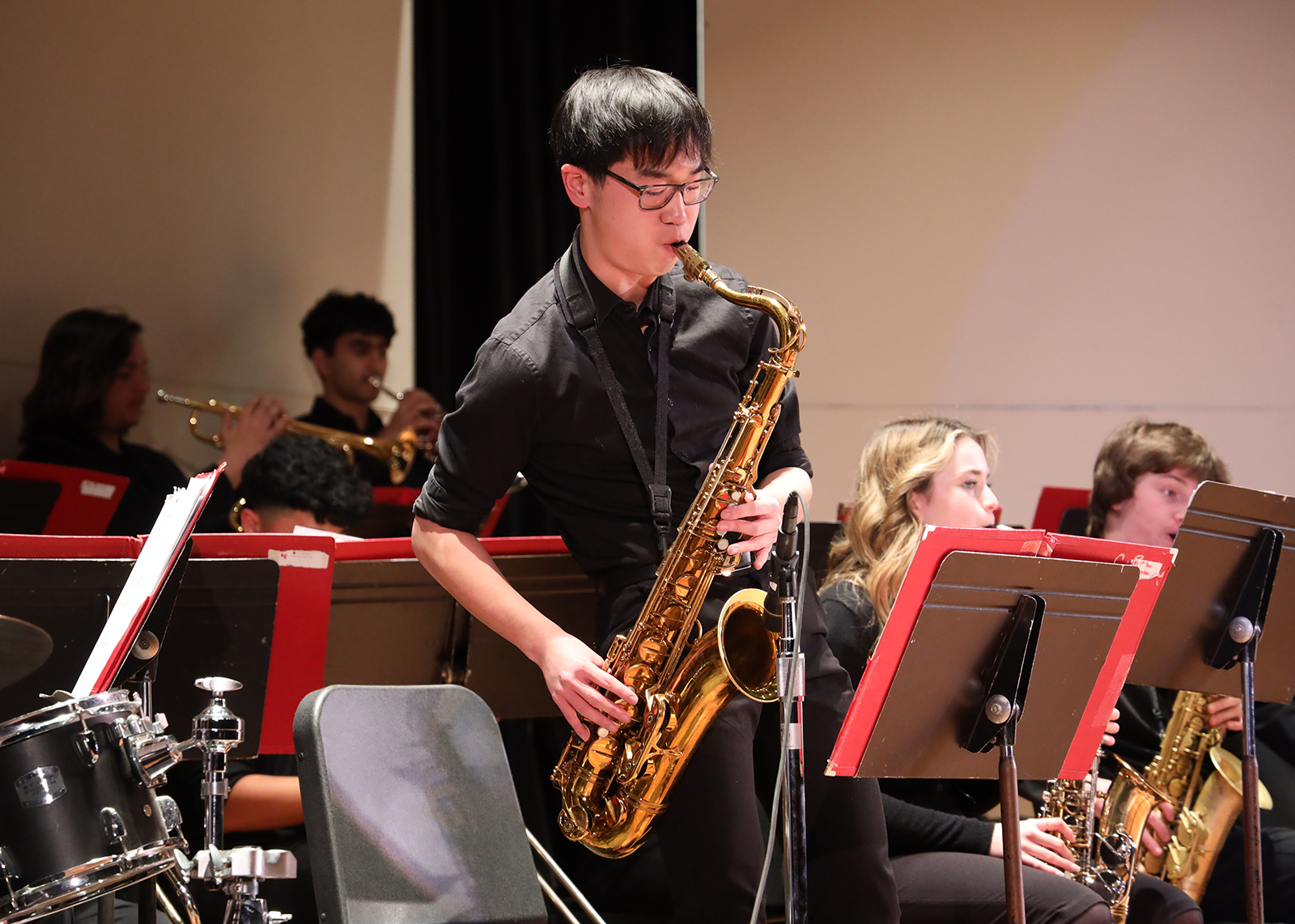 student standing playing saxophone on stage