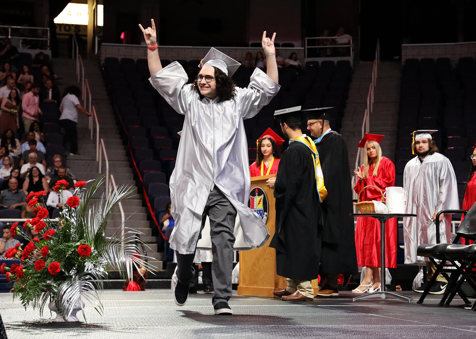 graduate giving the rock on sign crossing stage