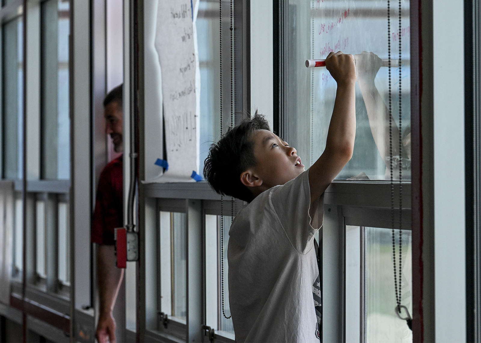 student writes on glass windows at STEM camp