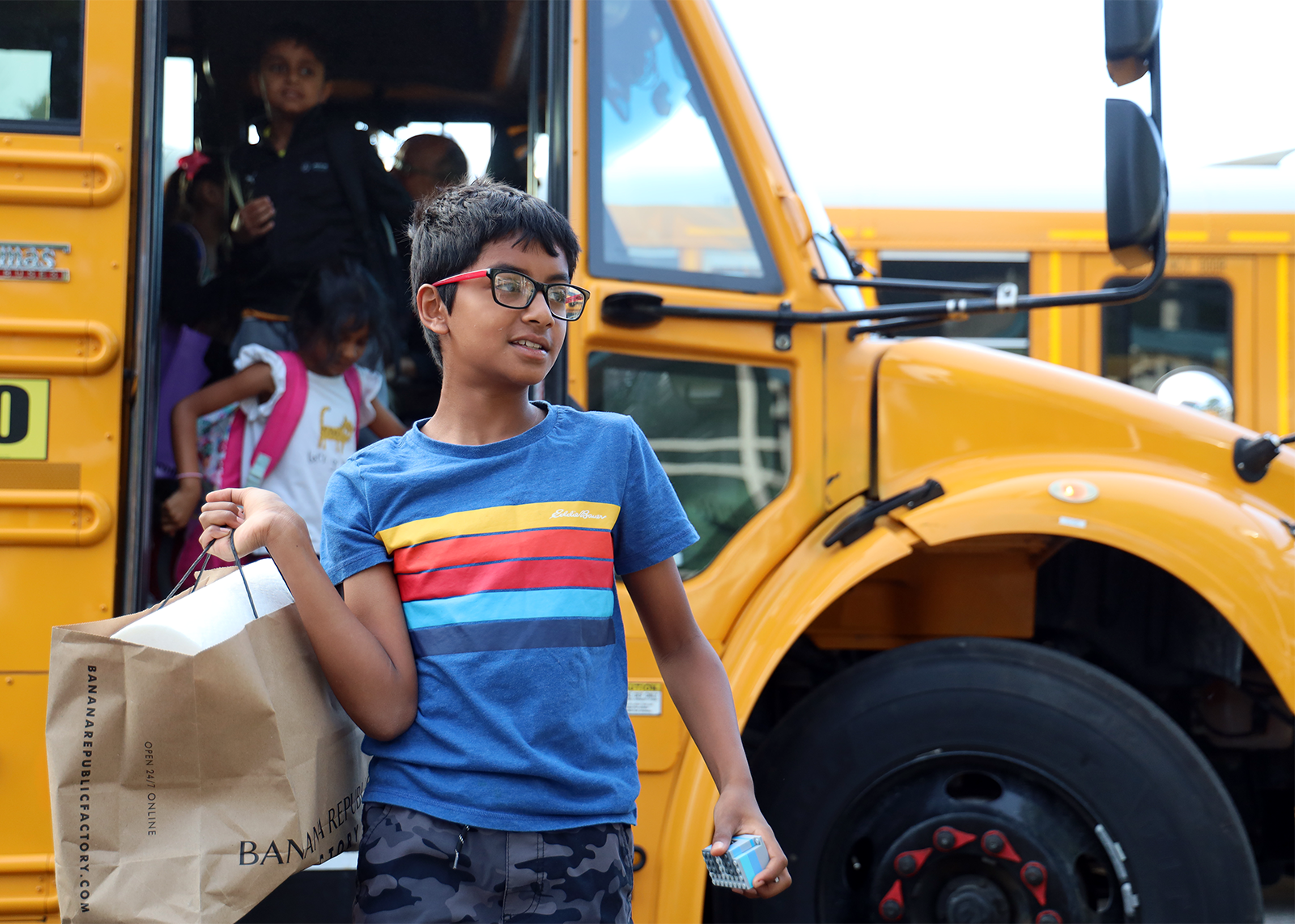 student getting off bus with supply bag over shoulder