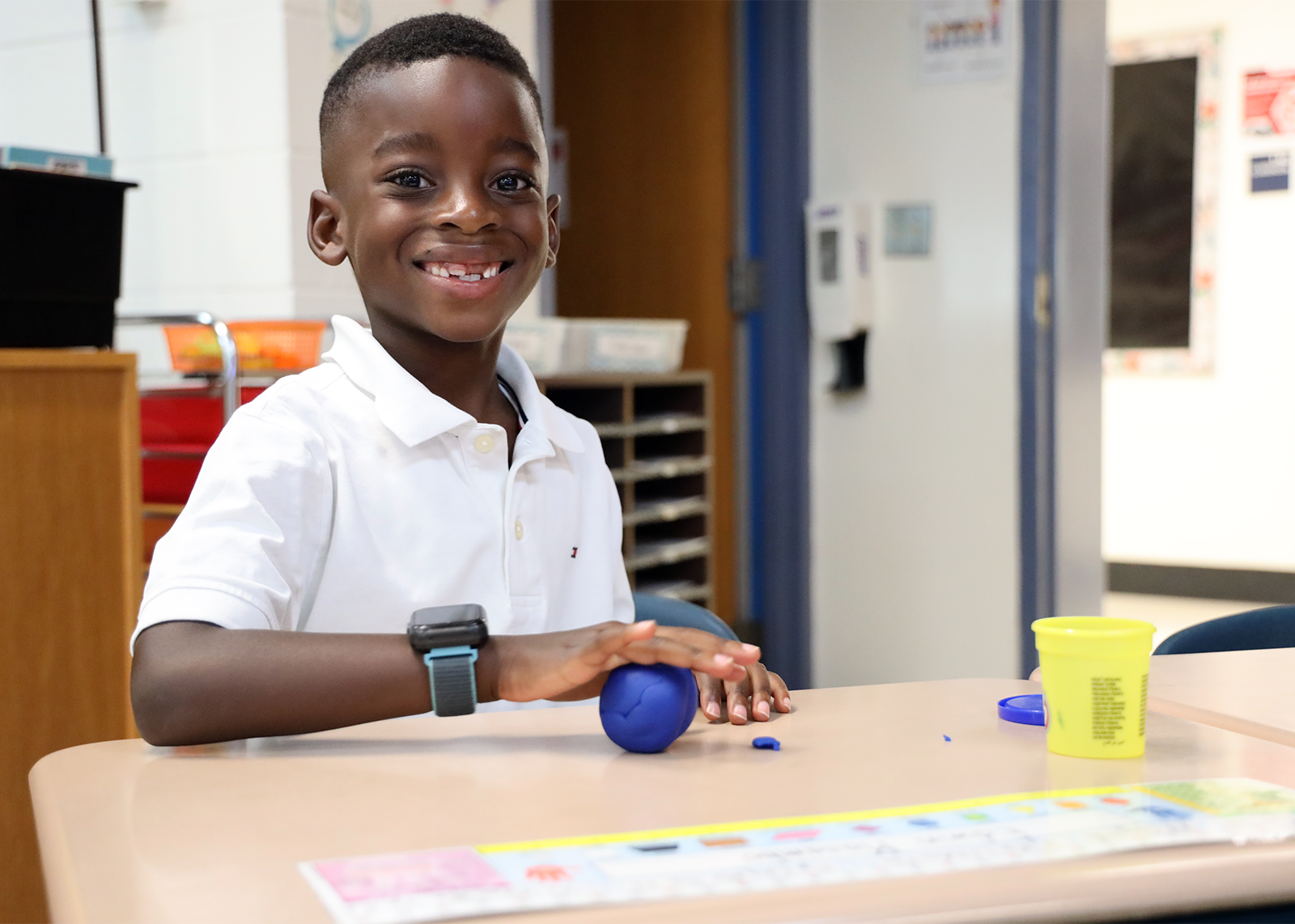 young student smiling while playing play-doh