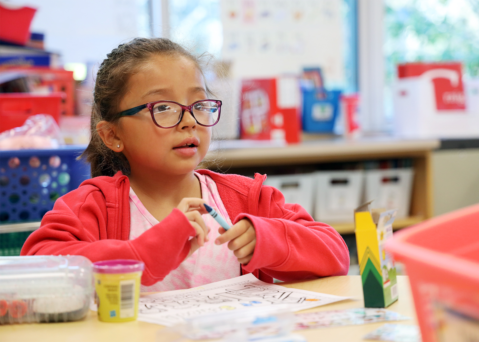 student with glasses gets ready to color