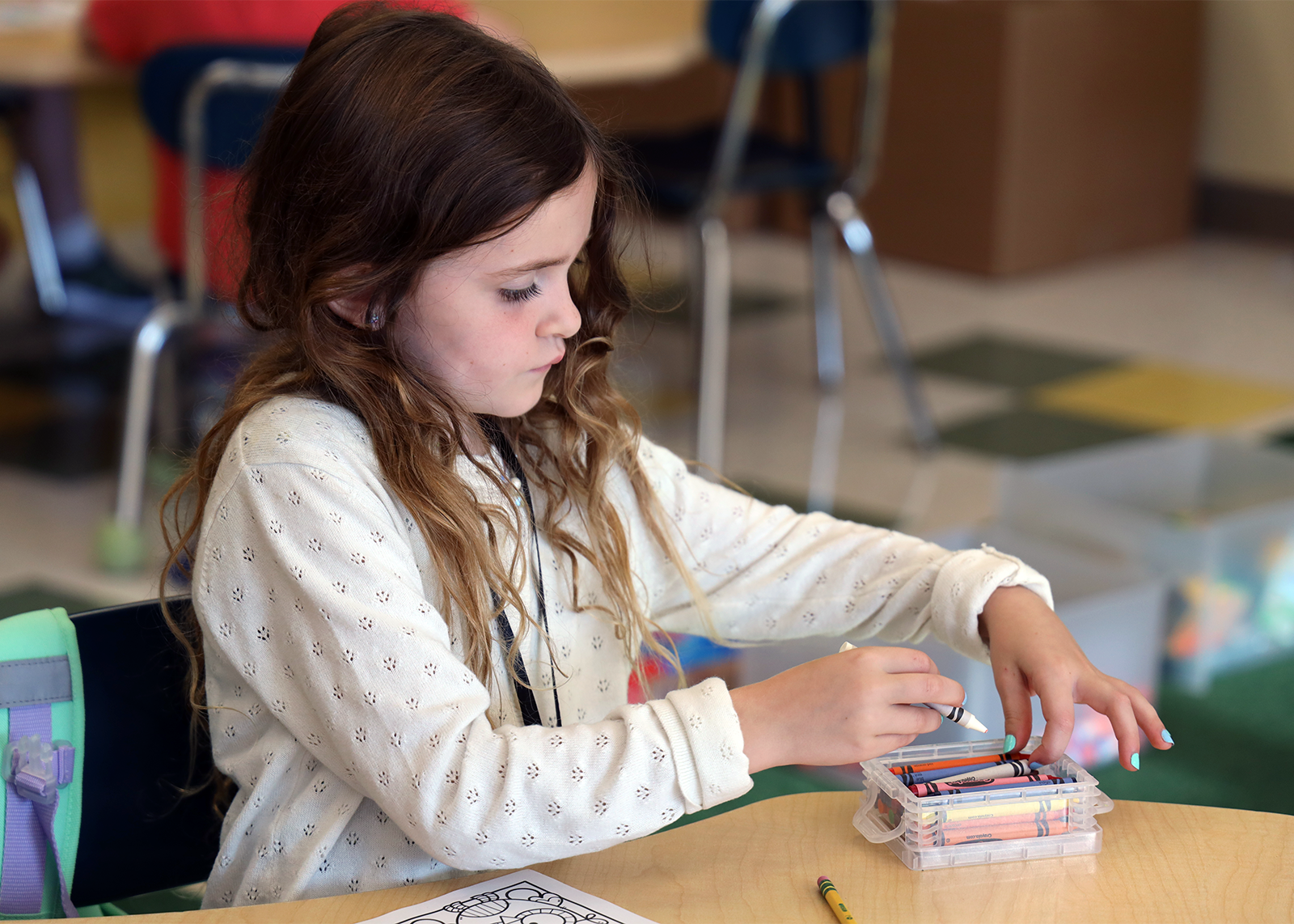 student focuses on coloring with crayons