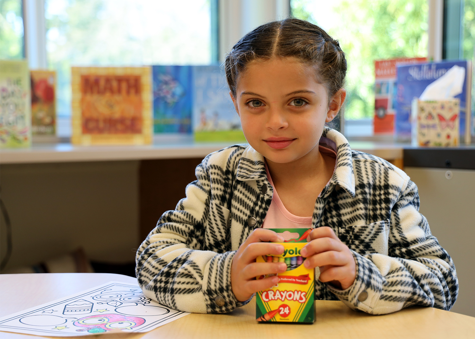 student smiling at camera while holding crayons