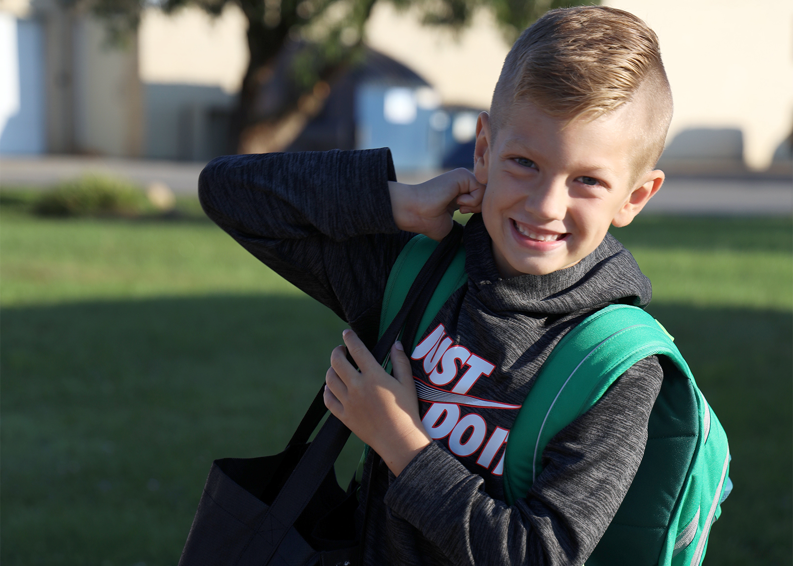 student smiles while adjusting backpack