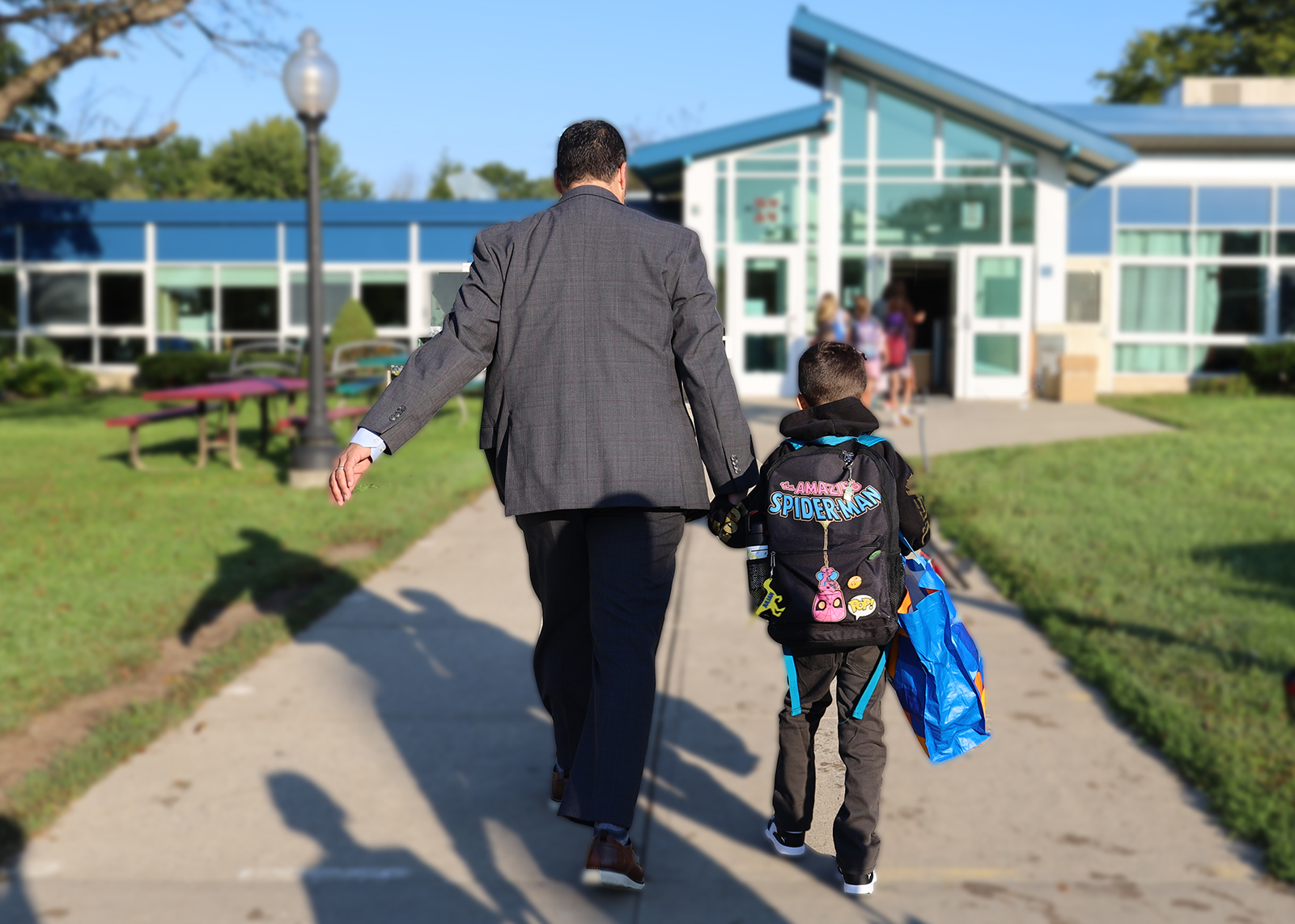 principal leads student into school holding hands