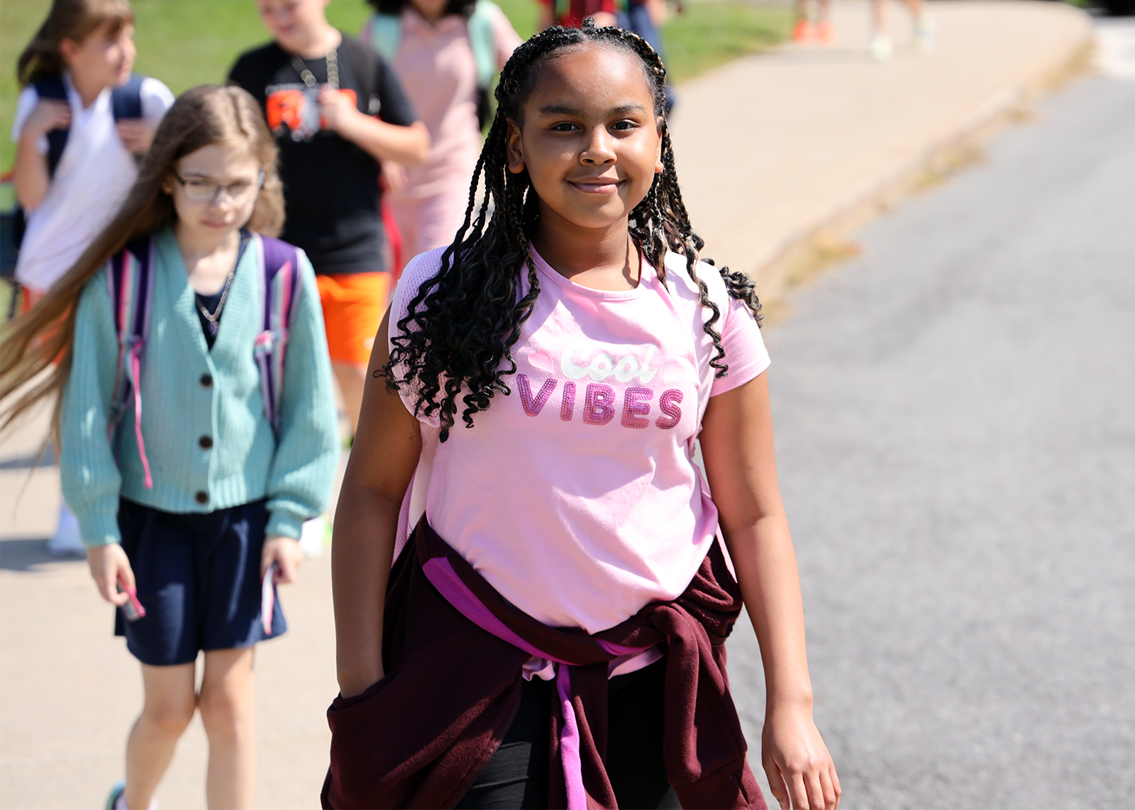 student smiles leaving school with shirt that says cool vibes