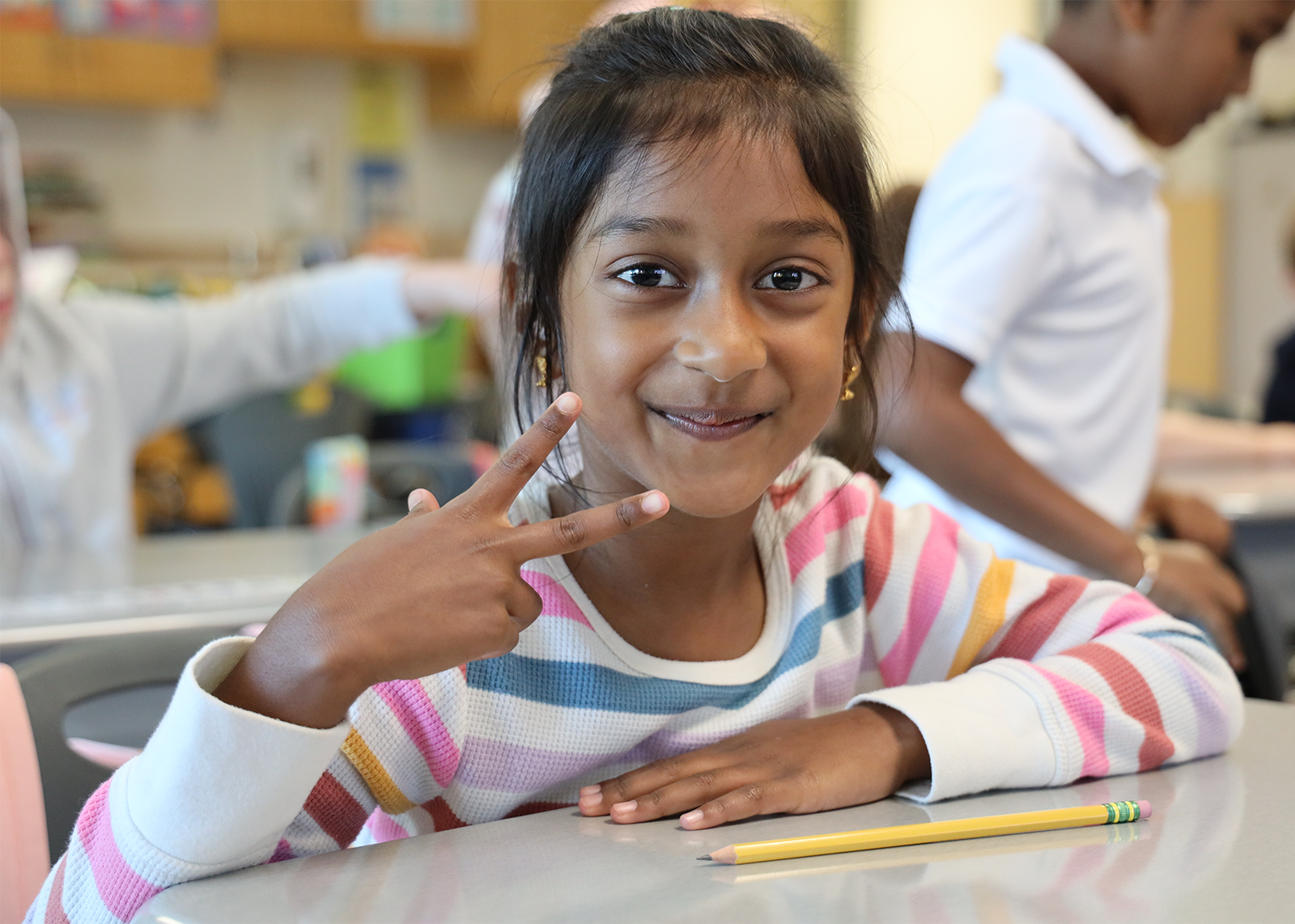 student smiles and gives peace sign