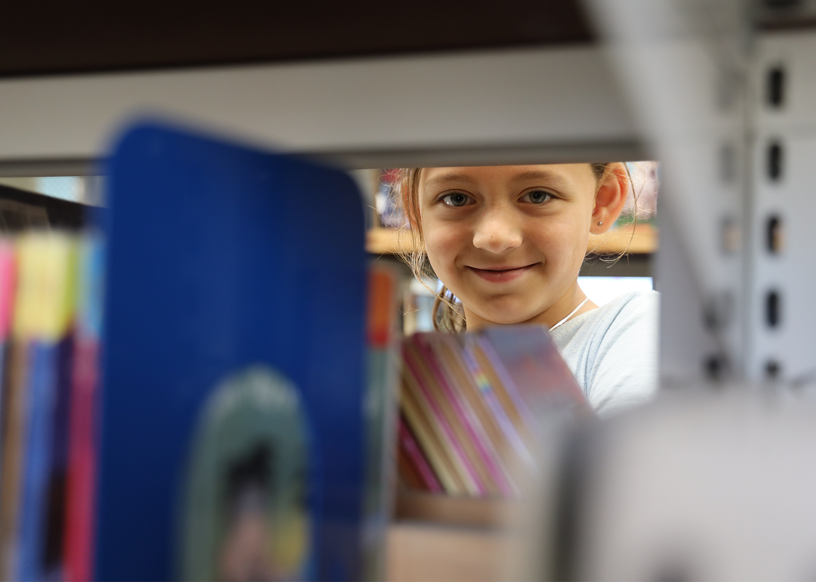 student smiling through rows of books