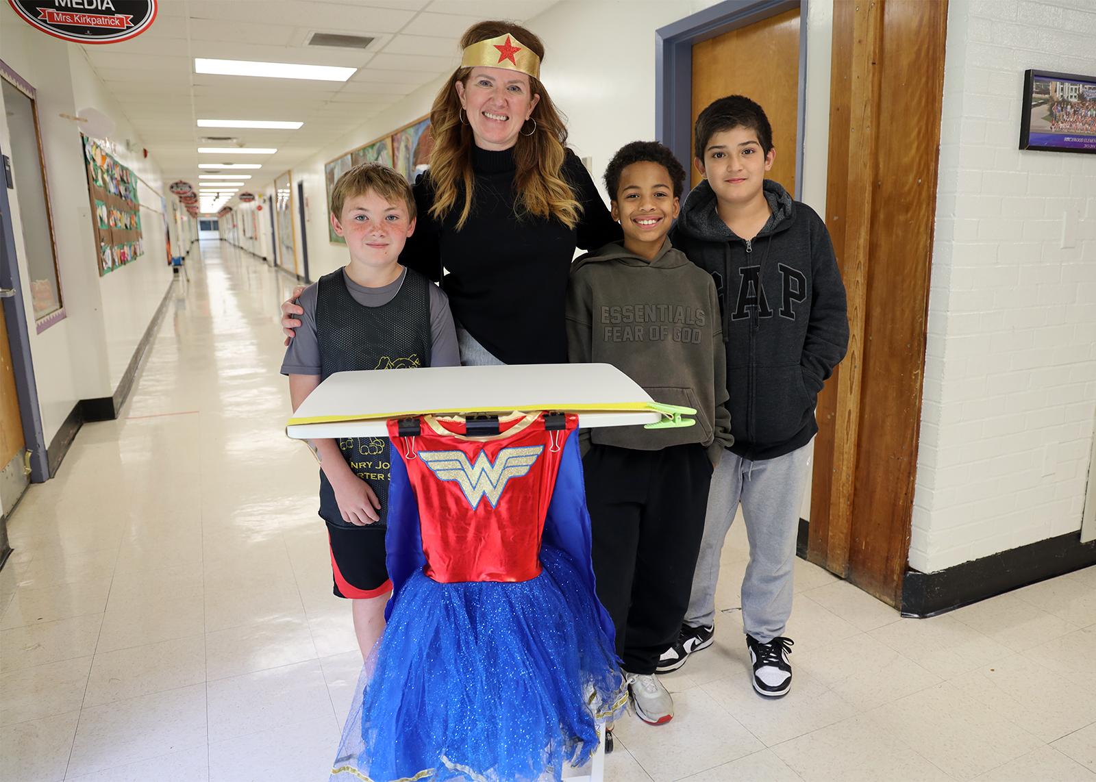 students smiling with principal and cart with wonder woman cape