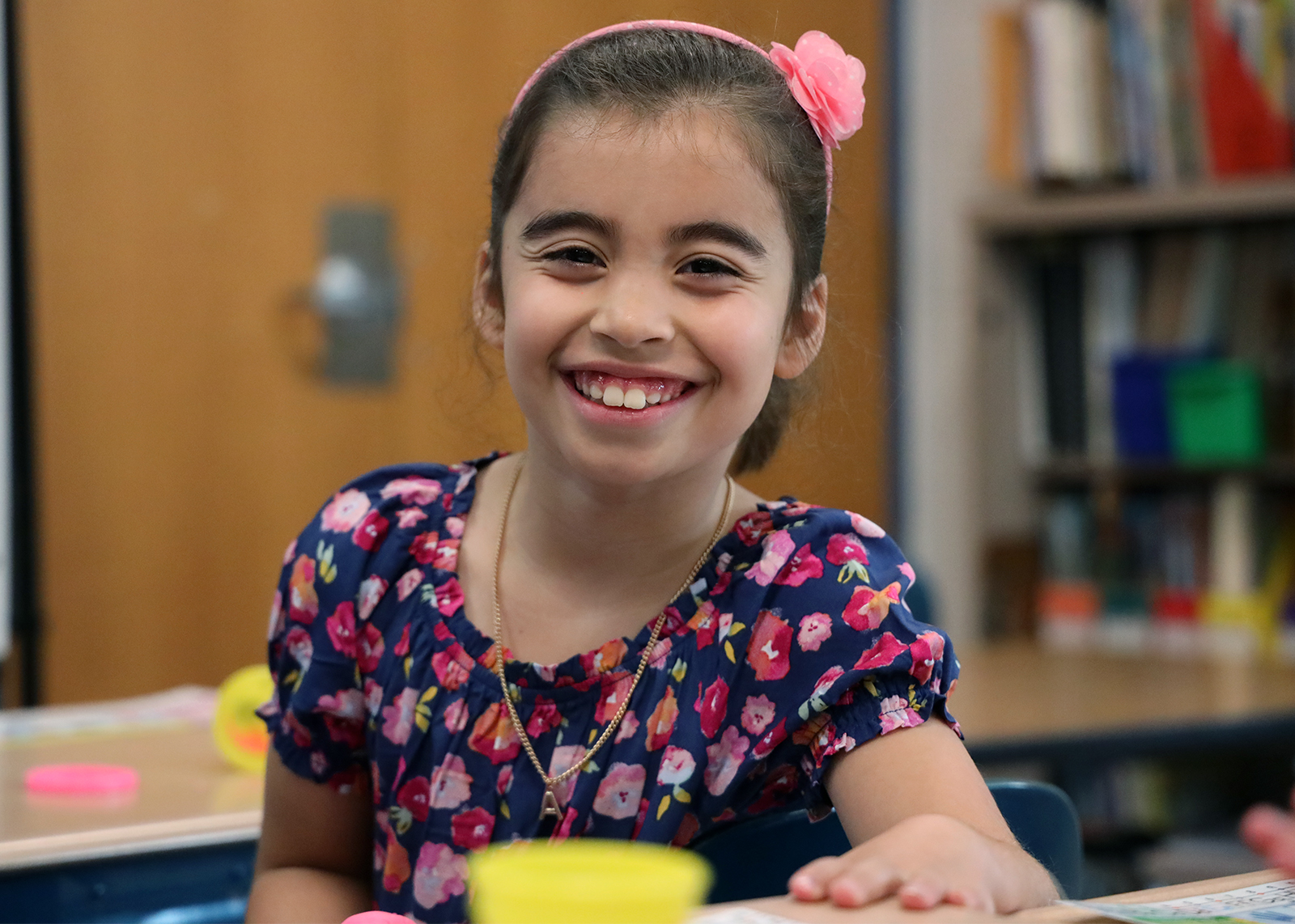 elementary student with bow in hair smiling at camera