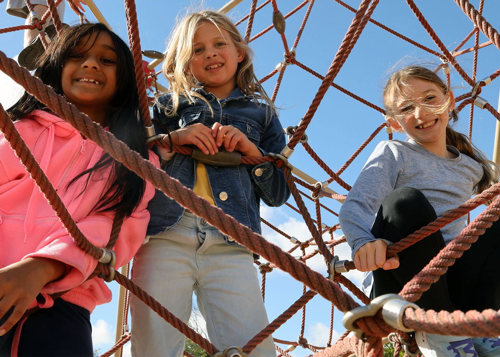 three students on cargo net looking down into camera