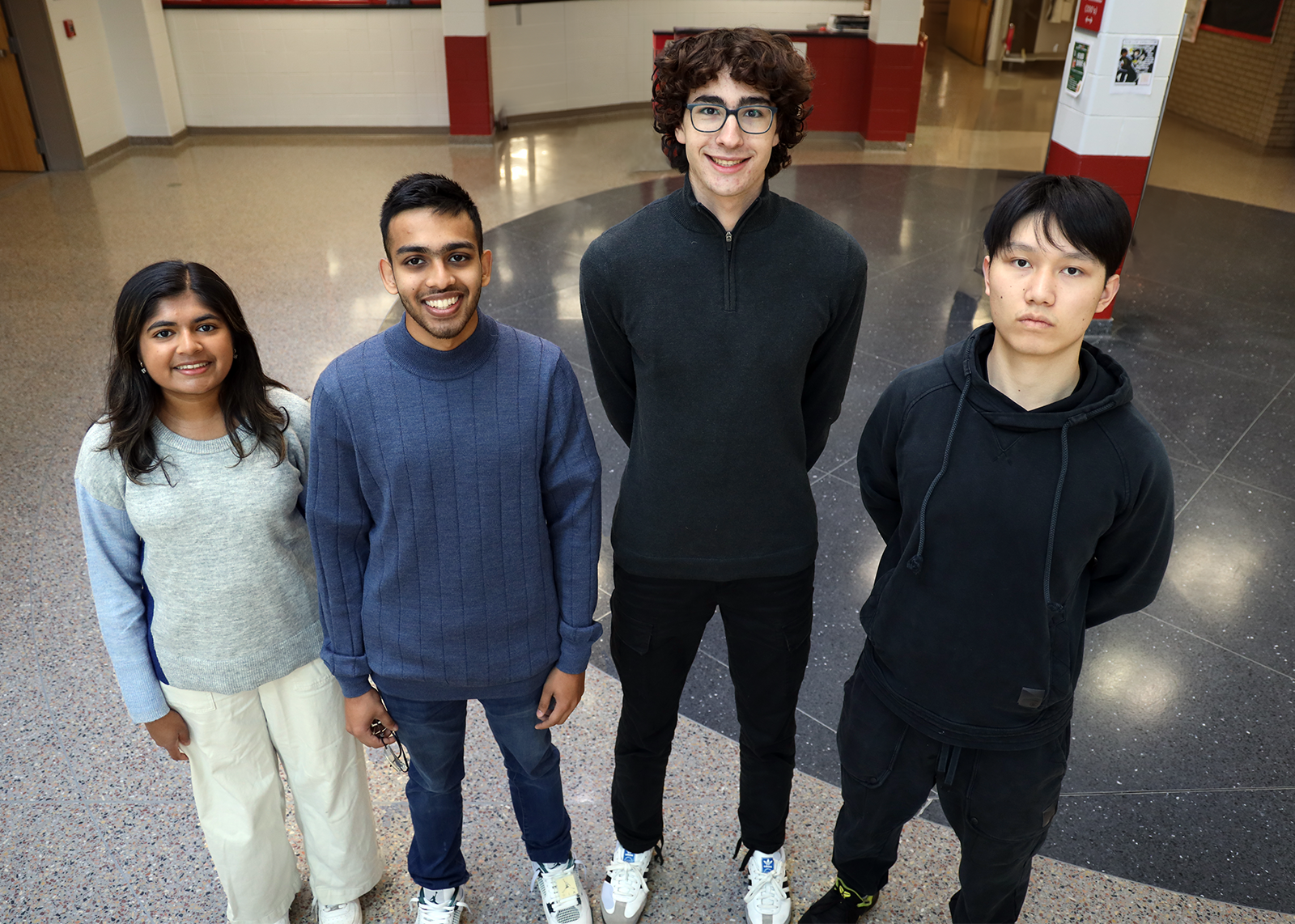 four high school students smiling in hallway