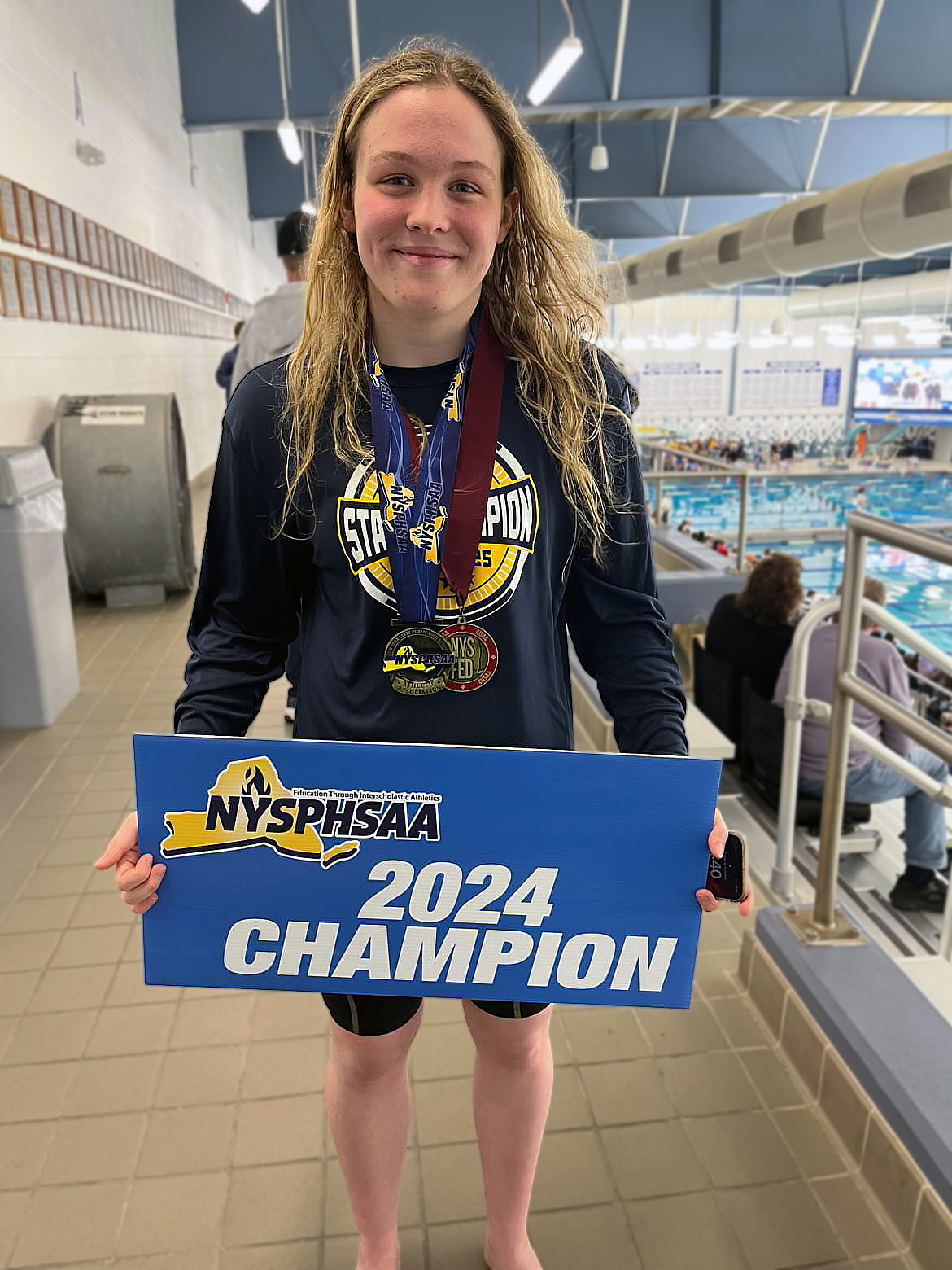 state champion swimmer holding sign that says 2024 champion