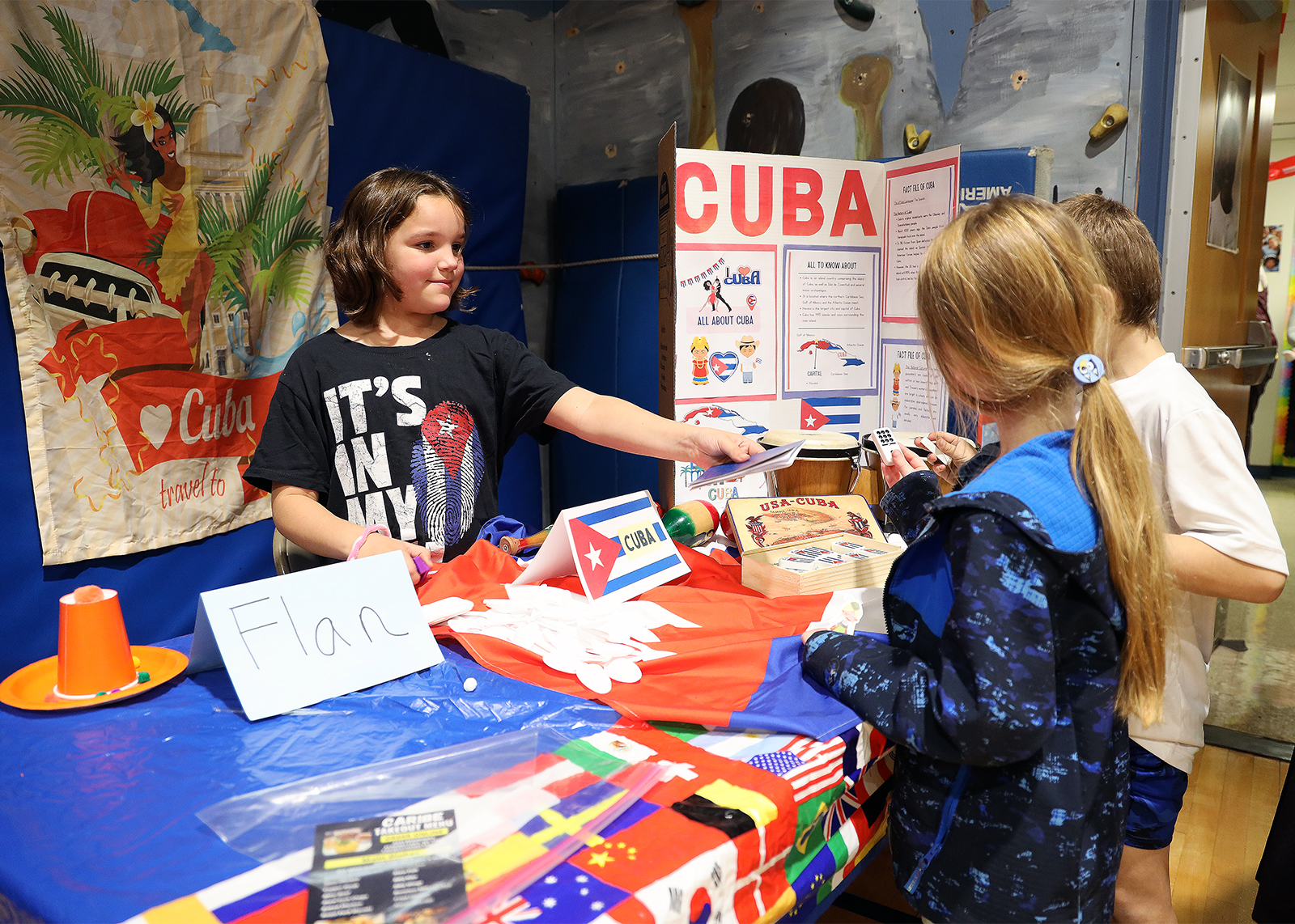 student at Cuba booth hands pretend passport to classmates