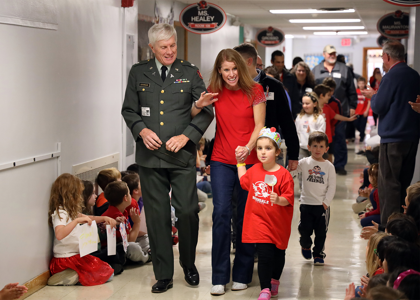 veteran arm and arm with teacher and grandchild in school hallway