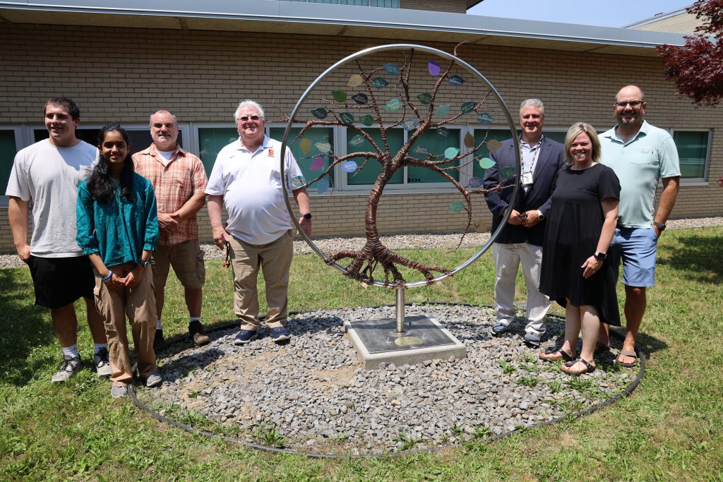 group of people standing with iron tree sculpture