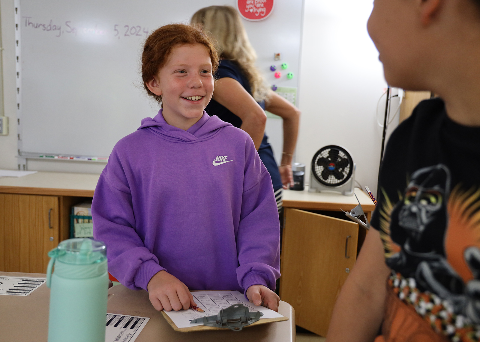 elementary student smiling holding clipboard