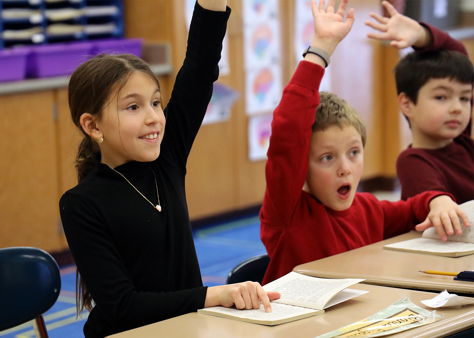 elementary schoolers raising hands