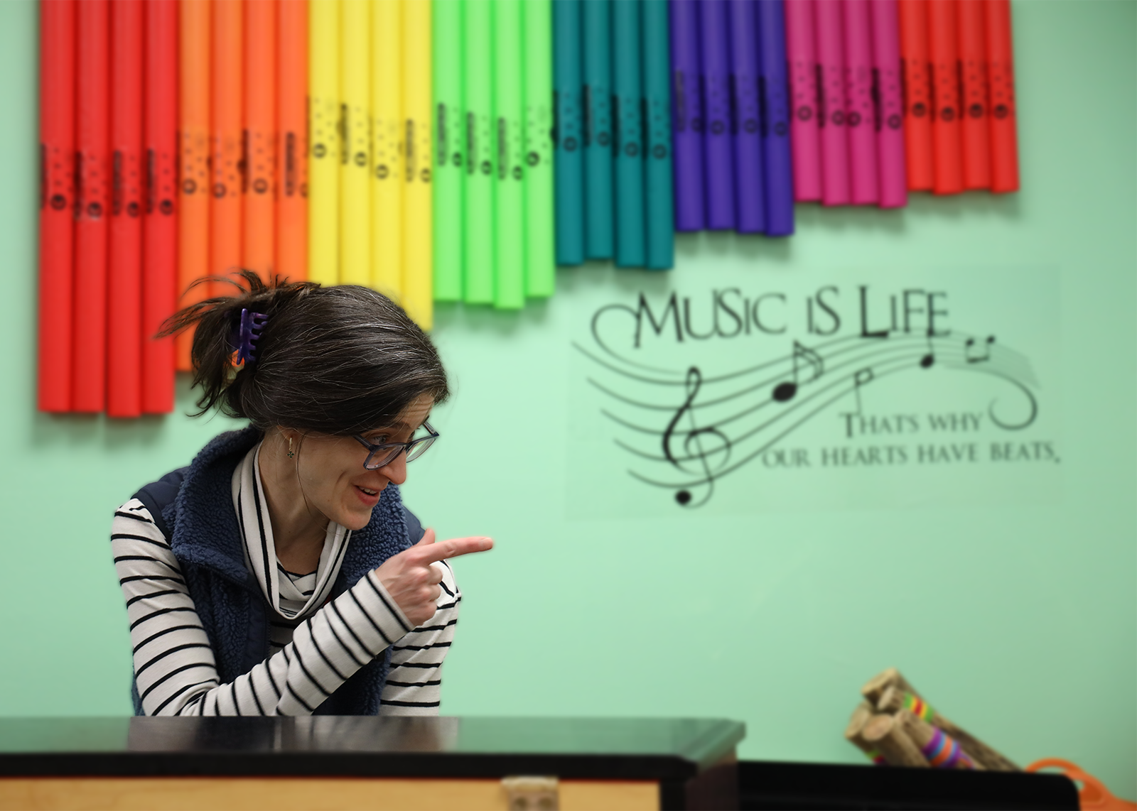 music teacher smiling with rainbow instruments behind her