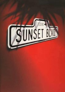 red image with white Sunset Boulevard road sign, palm tree shadow. 