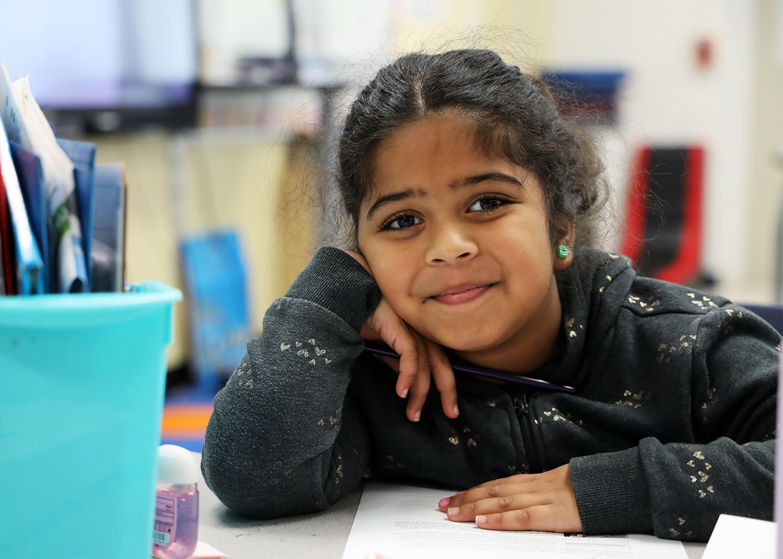 elementary student leabing on desk smiling