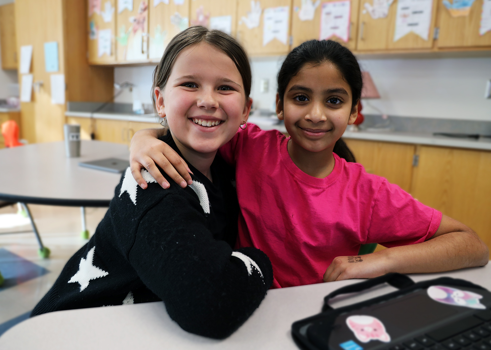 friends in class smiling with computer in forground