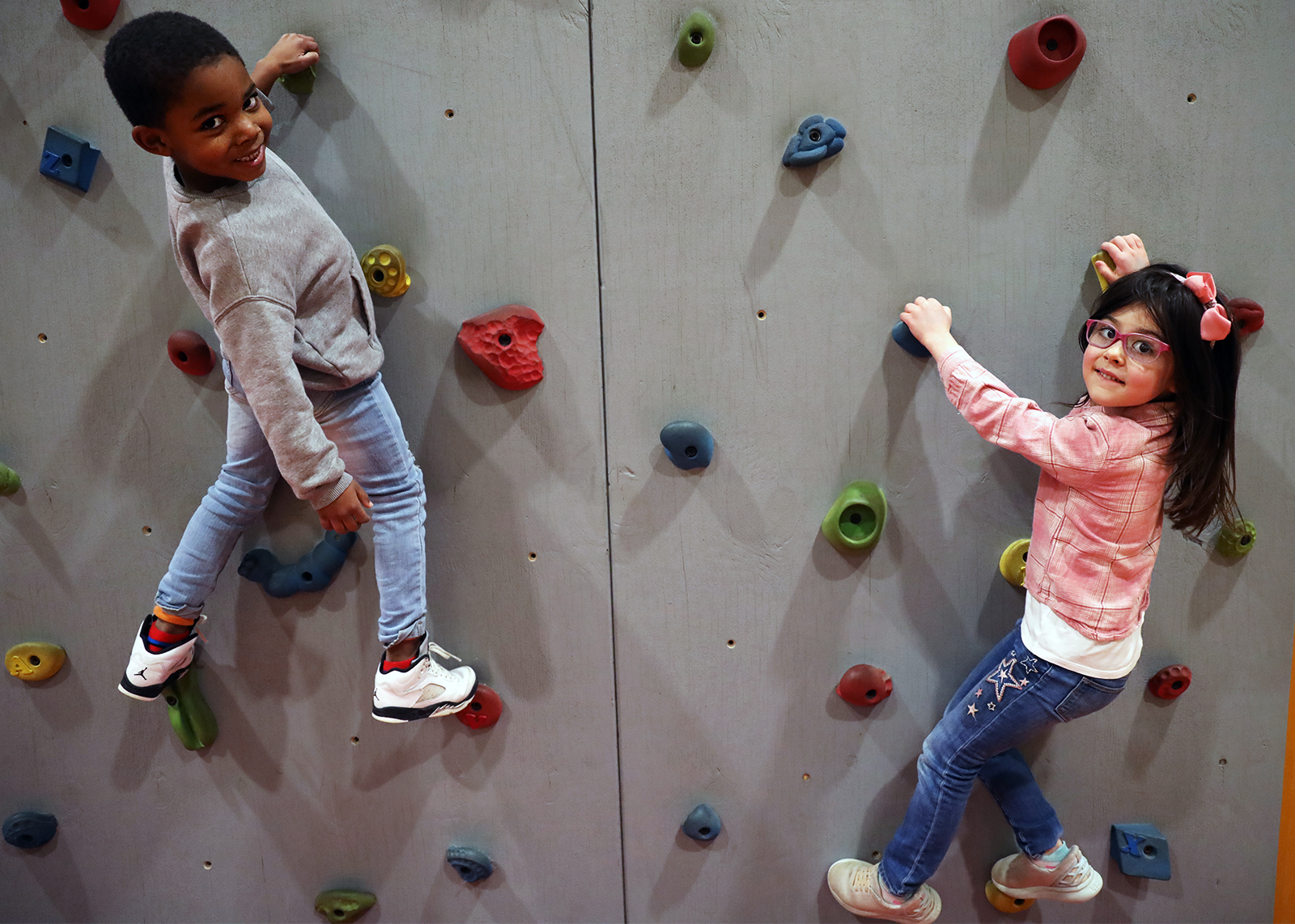 kindergartners climb rock wall and smile