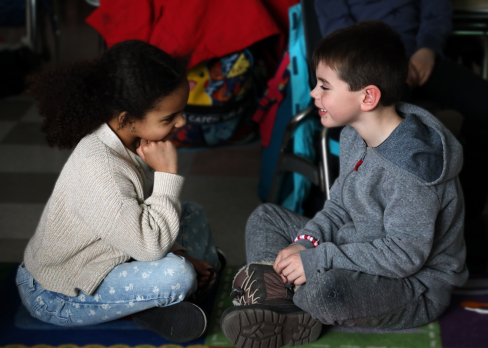 two first graders sitting on the floor listening to one another