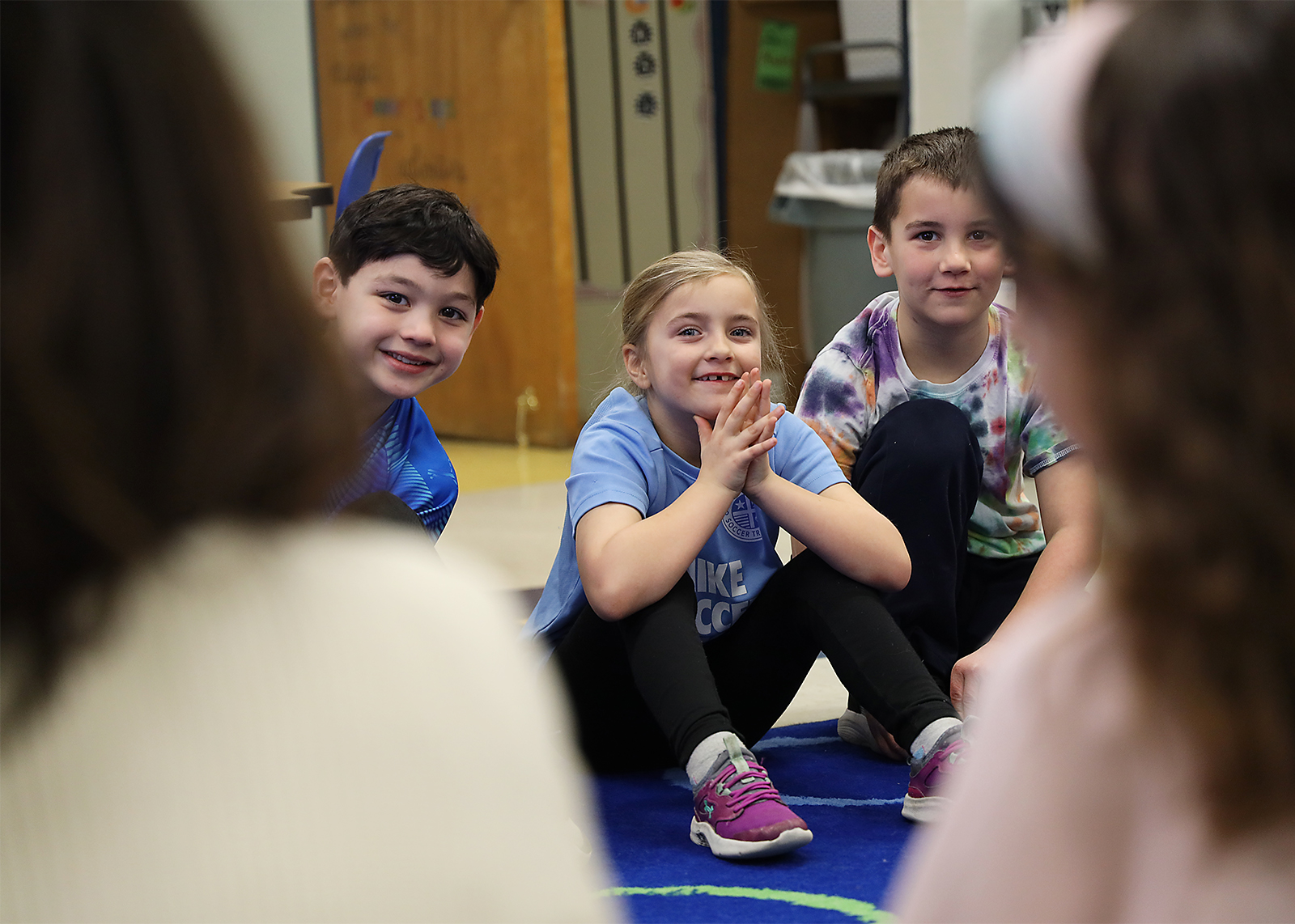 second graders peek around classmates to smile at camera